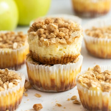 one cheesecake unwrapped sitting on top of another apple cheesecake in a muffin wrapper.