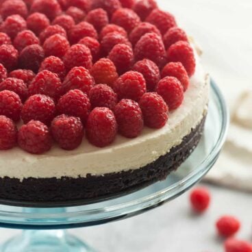 This Brownie Bottom Cheesecake is made with a fudgy, brownie base, a silky smooth no bake cheesecake and topped with piles of fresh raspberries. It's an elegant holiday dessert that's also naturally gluten free!