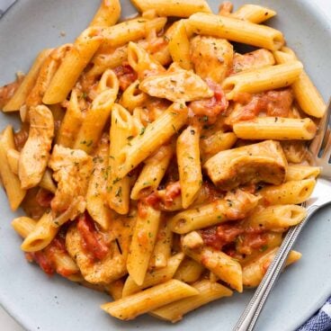 overhead image of cajun chicken pasta on blue plate with fork.