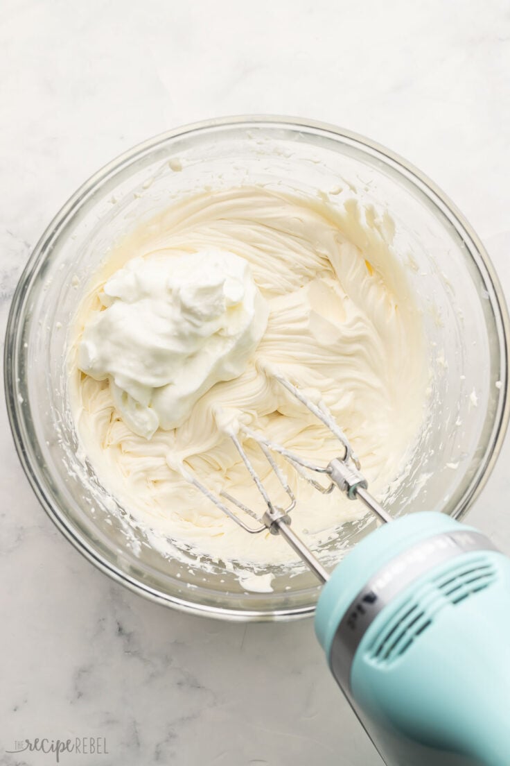 mixed cream cheese in a glass mixing bowl with greek yogurt added.