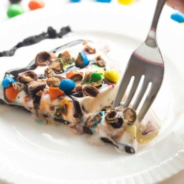 This Frozen Ice Cream Dessert Pizza is THE no bake summer dessert you need! A Dairy Queen Copycat Treatzza Pizza, it has an Oreo fudge crust topped with ice cream, fudge sauce and M&M's! https://www.thereciperebel.com/frozen-ice-cream-dessert-pizza-treatzza-pizza/