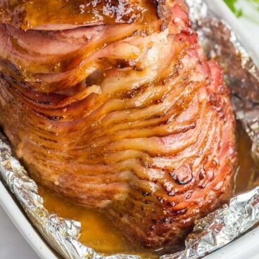 whole spiral ham in baking dish with honey glaze