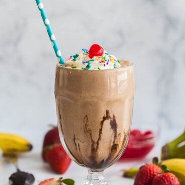 chocolate milkshake in tall glass with paper straw