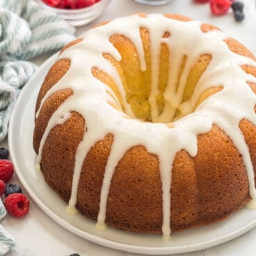 whole glazed lemon bundt cake with blueberries and raspberries in background