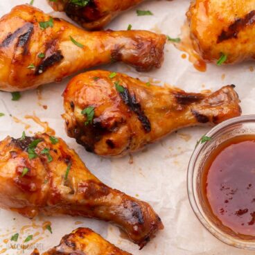 close up view of grilled chicken drumsticks with maple glaze beside.