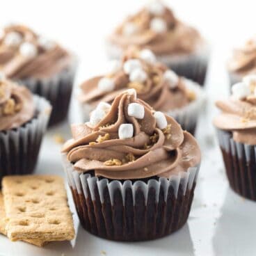 nutella smores cupcakes on white cake plate with crushed graham crumbs and marshmallow bits