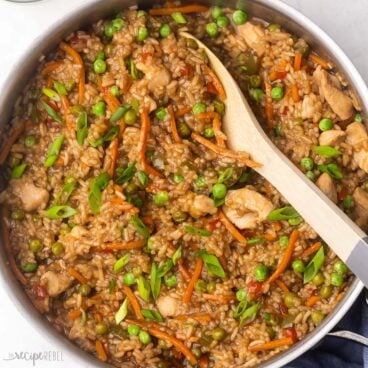 close up of cooked teriyaki chicken and rice with wooden ladle in pan.