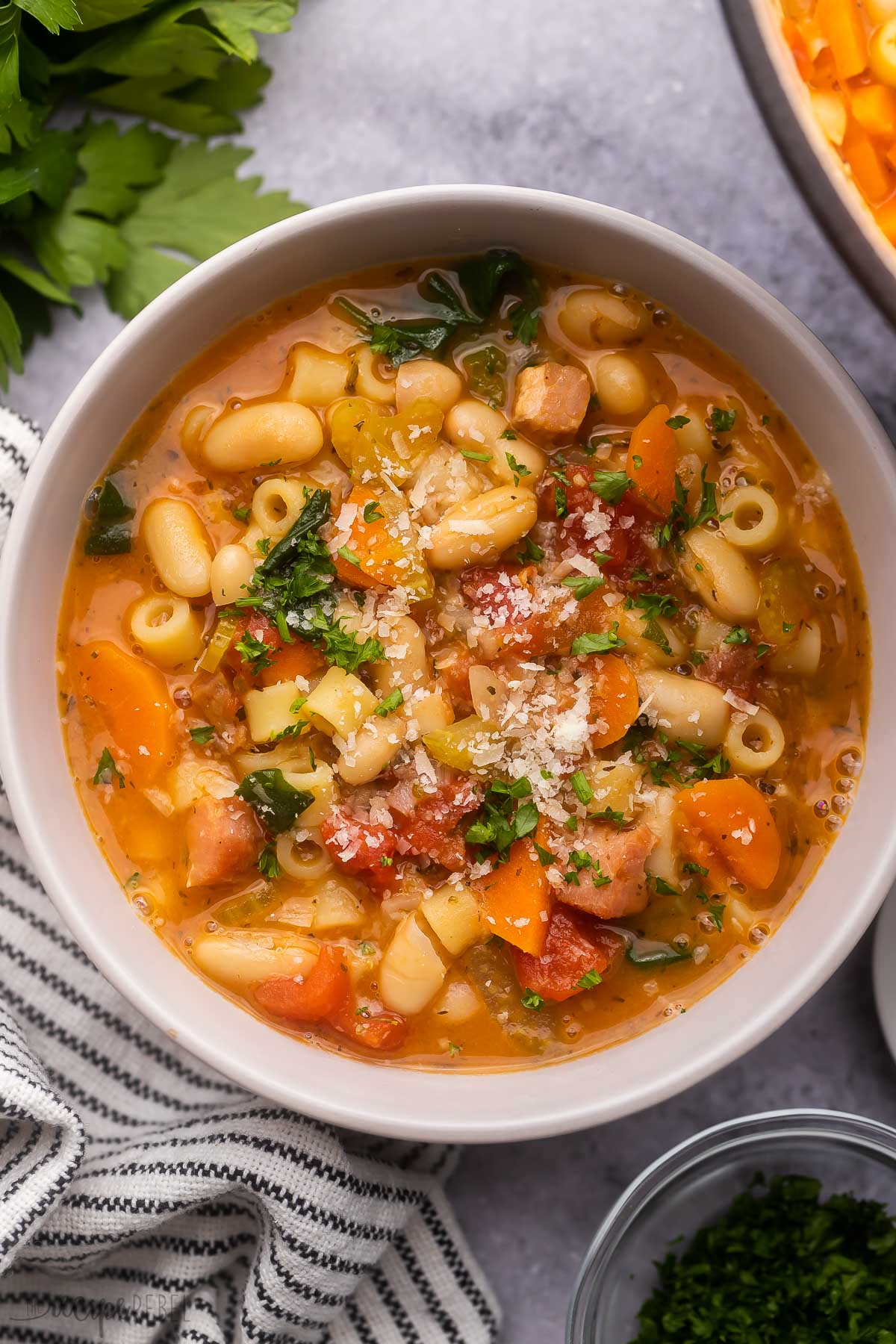overhead view of a bowl of pasta fagioli topped with parsley and parmesan.