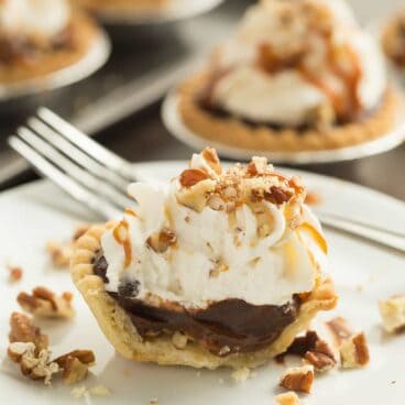 Turtle Pudding Pie Minis are the perfect bite-sized treat (made in tart shells!) for the holidays or any party -- they come together quickly and are loaded with pecans, caramel, chocolate pudding and topped with whipped cream!
