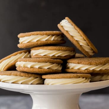 white chocolate gingersnap oreos piled on a white cake plate